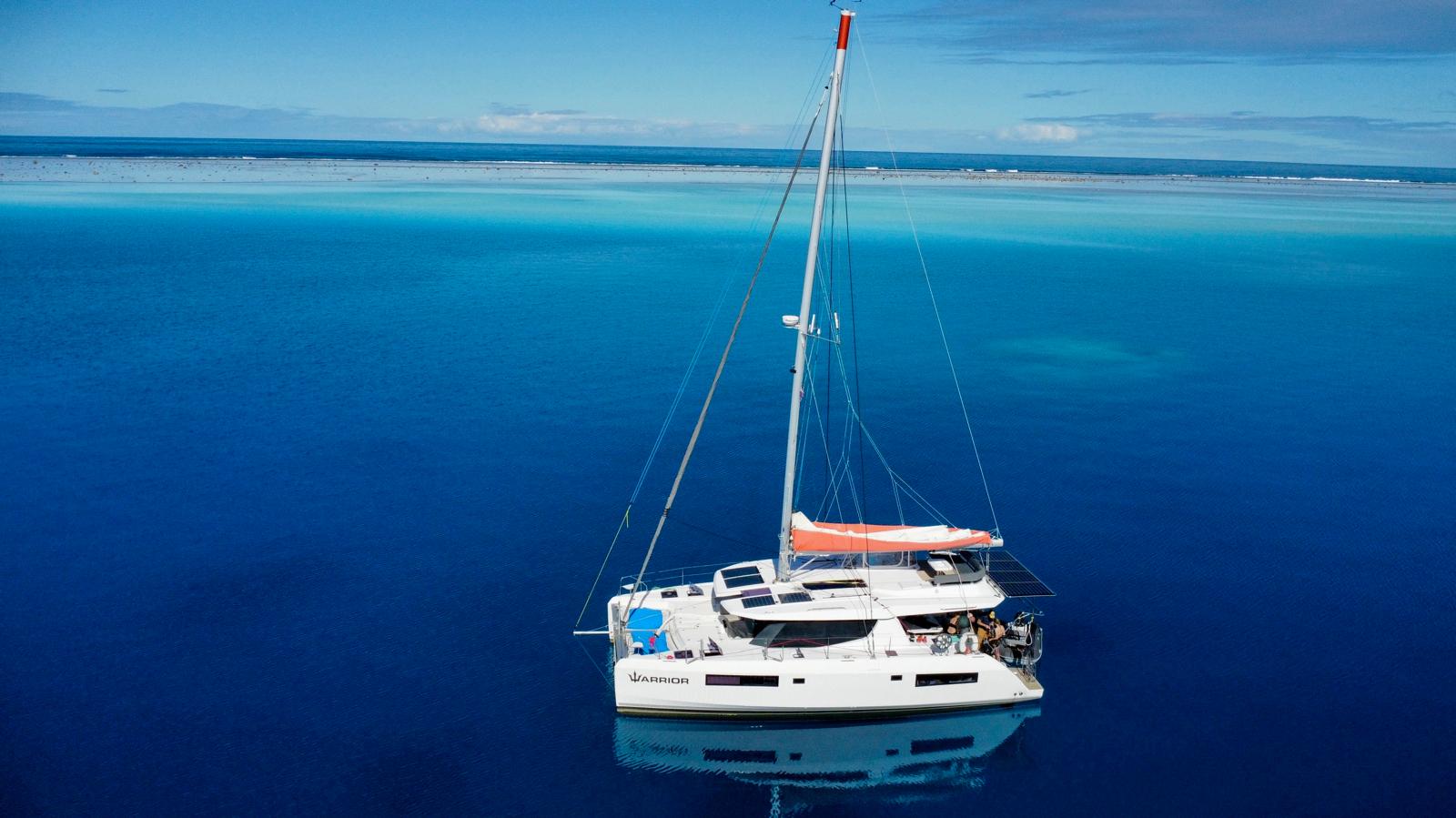 Warrior, our Leopard 45 catamaran, at anchor in clear blue water inside a reef